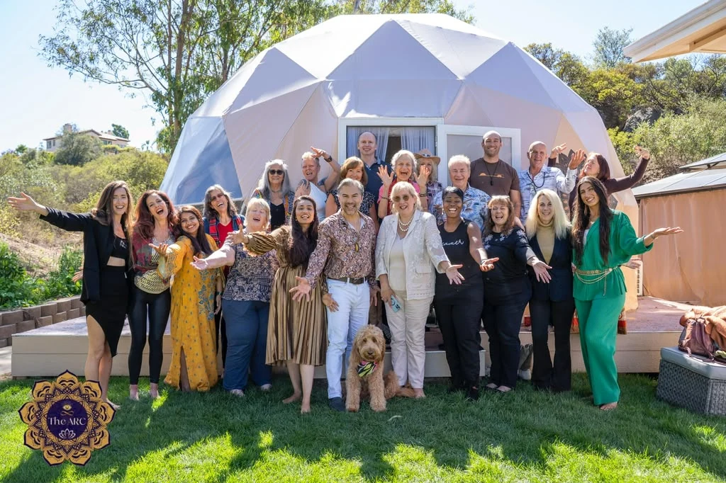 A retreat community gathered with Sage in front of The Abundance Dome